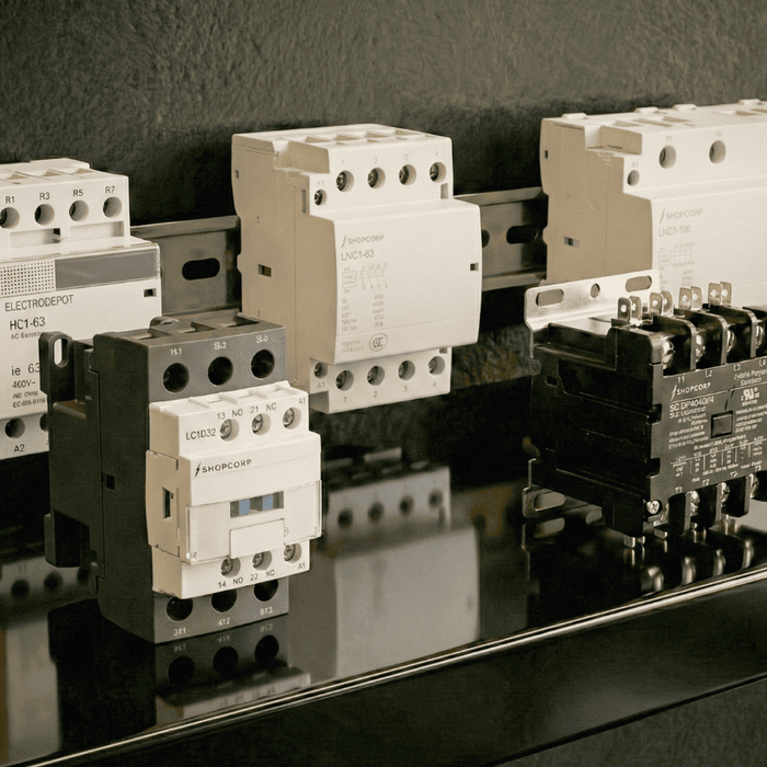 Multiple electrical contactors mounted on a DIN rail and displayed on a reflective surface, showing different sizes and configurations for industrial and HVAC control applications